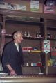 Eigenaar achter de toonbank met geneesmiddelen achter hem in de schappen Kluisstraat 2-4, rond 1960. Voor meer details klik hier.
