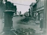 Panden die tijdens de granaatweken in 1944 zwaar werden beschadigd. Zicht op de Hoofdstraat vanaf de pomp richting het zuiden. Planken voor de ramen van Ausems herenkleding. Voor meer details klik hier.