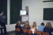 Leerlingen in leslokaal kijken naar tv met videorecorder op de huishoudschool. Voor meer details klik hier.